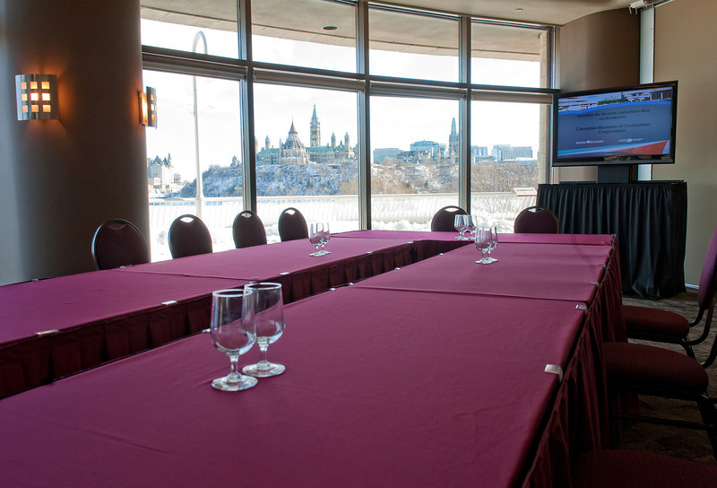 A conference room with a table and chairs and a tv.