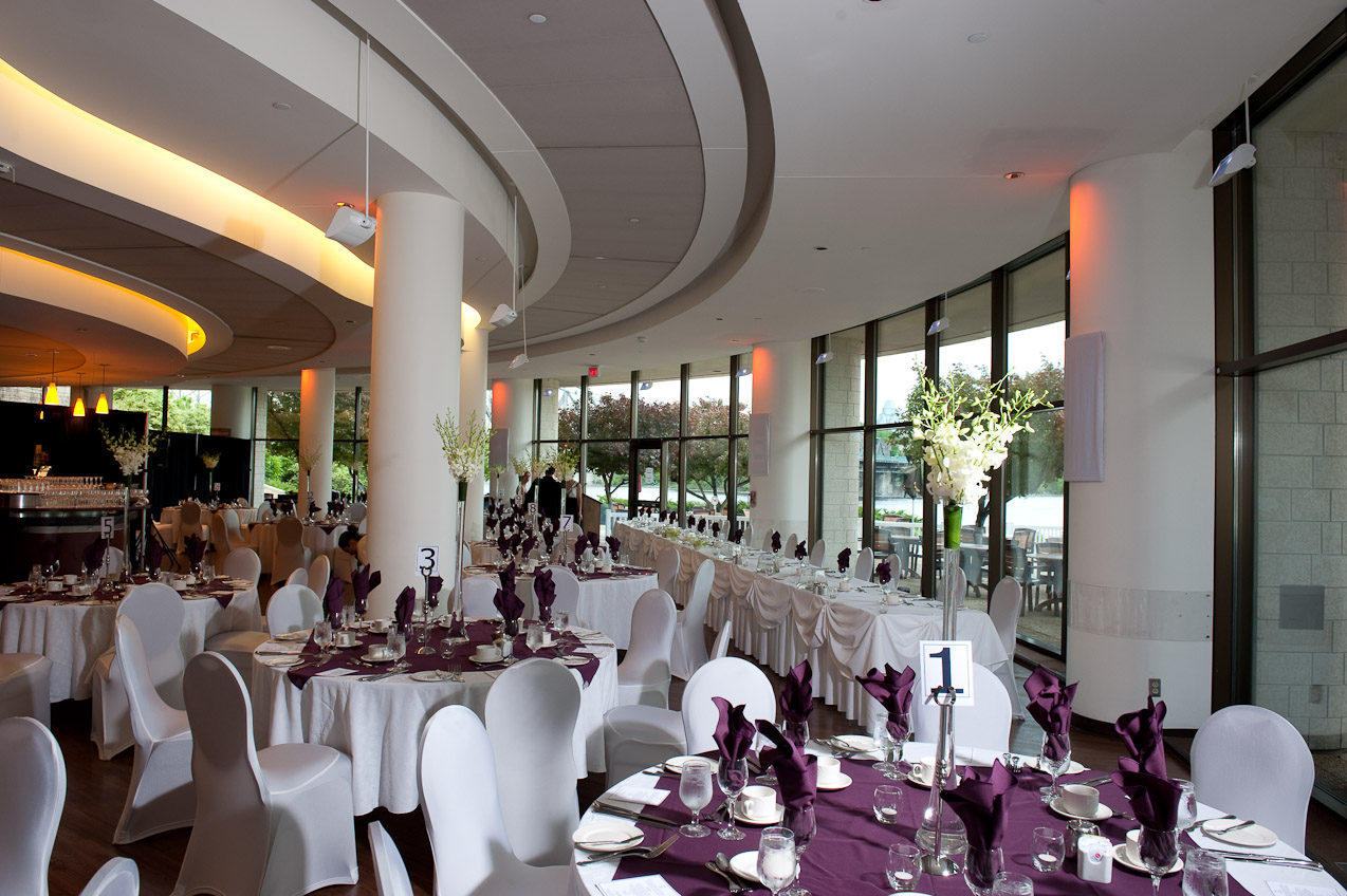 A banquet hall with white and purple tablecloths.