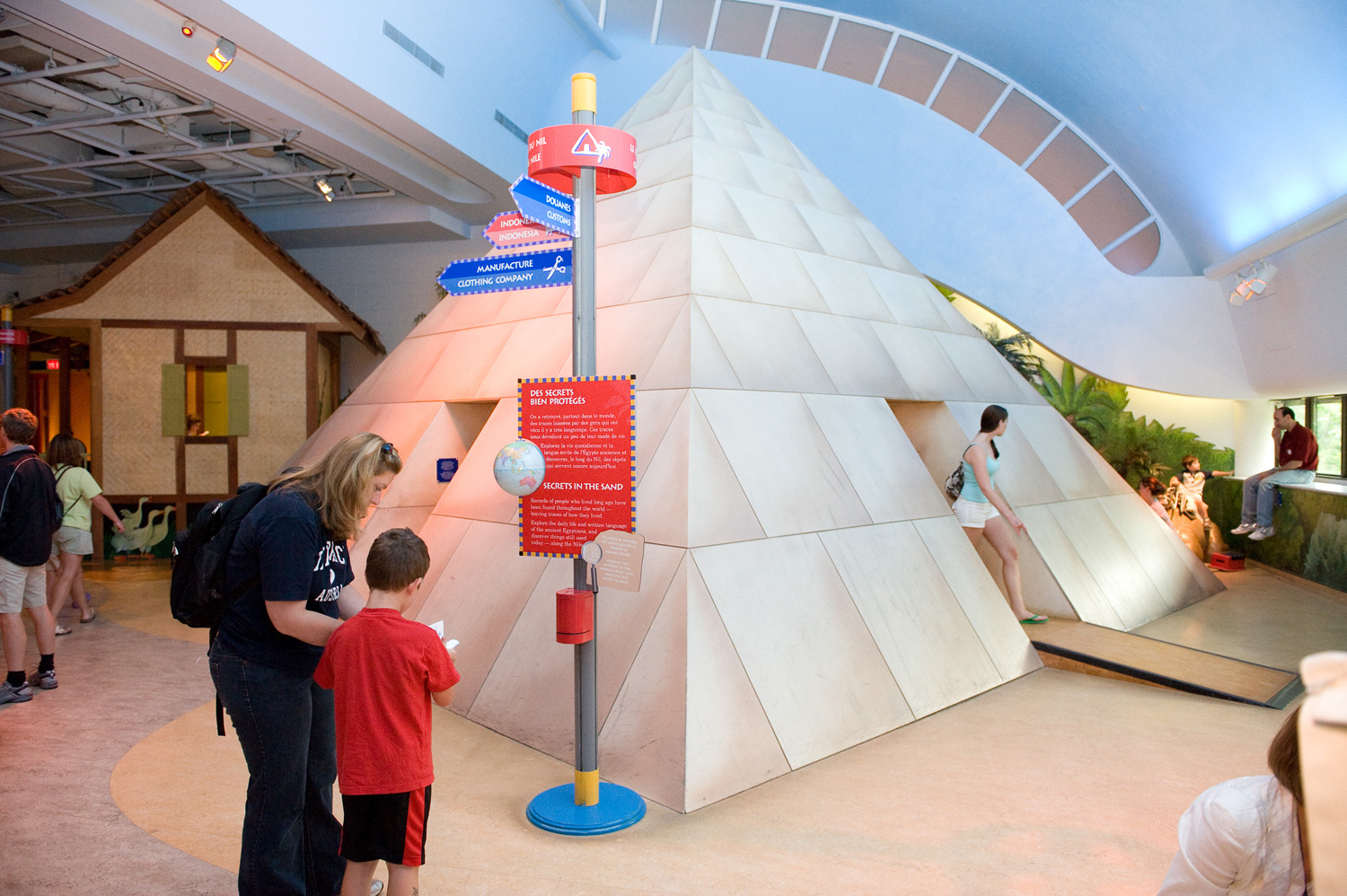 A group of people gathering in a history hall to marvel at a pyramid exhibit.