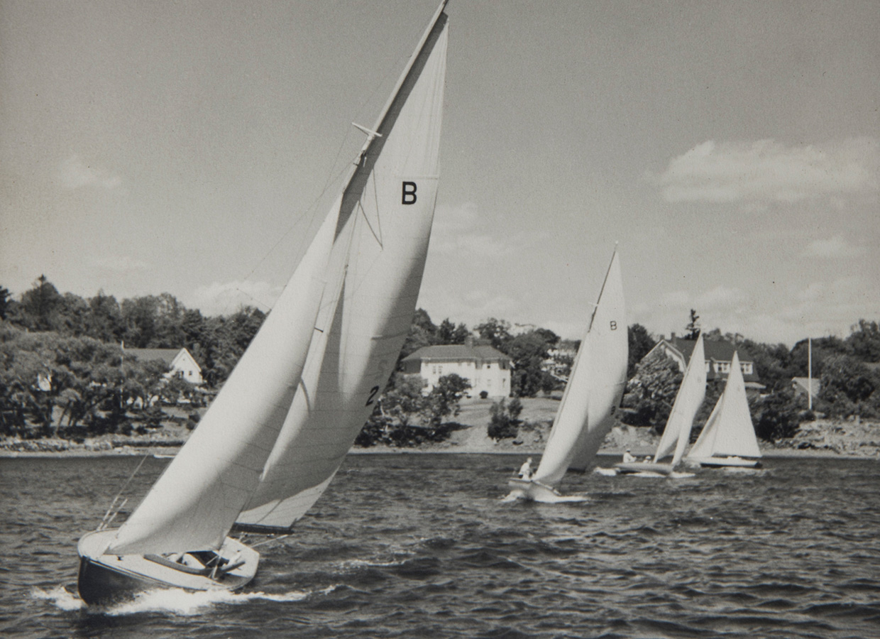 A group of sailboats racing on a body of water near the Canadian Museum of History in Ottawa.