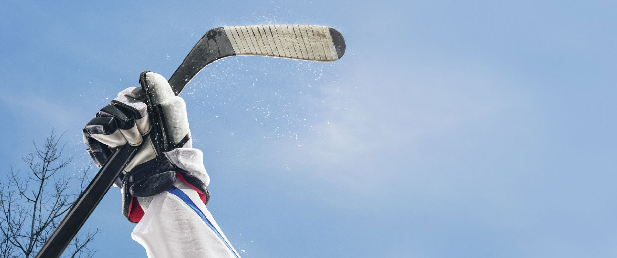 A hockey player is holding a hockey stick up in the air at the Canadian Museum of History.