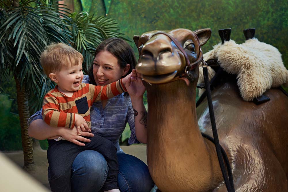 A woman and a child petting a camel statue at the Canadian Museum of History in Ottawa.