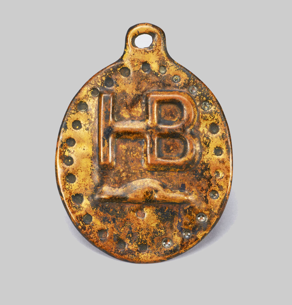 A bronze medallion with the letter h on it showcased at the Canadian Museum of History.