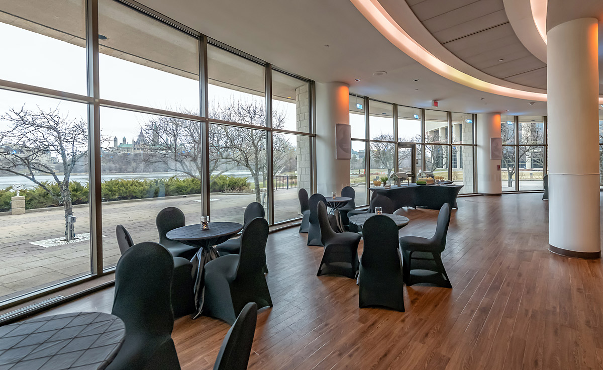 The Canadian Museum of History in Ottawa houses a large room adorned with black tables and illuminated by ample natural light through its large windows.