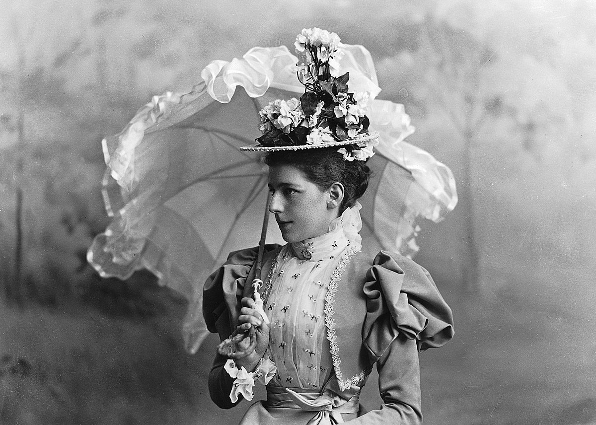 An old photo of a woman holding an umbrella.