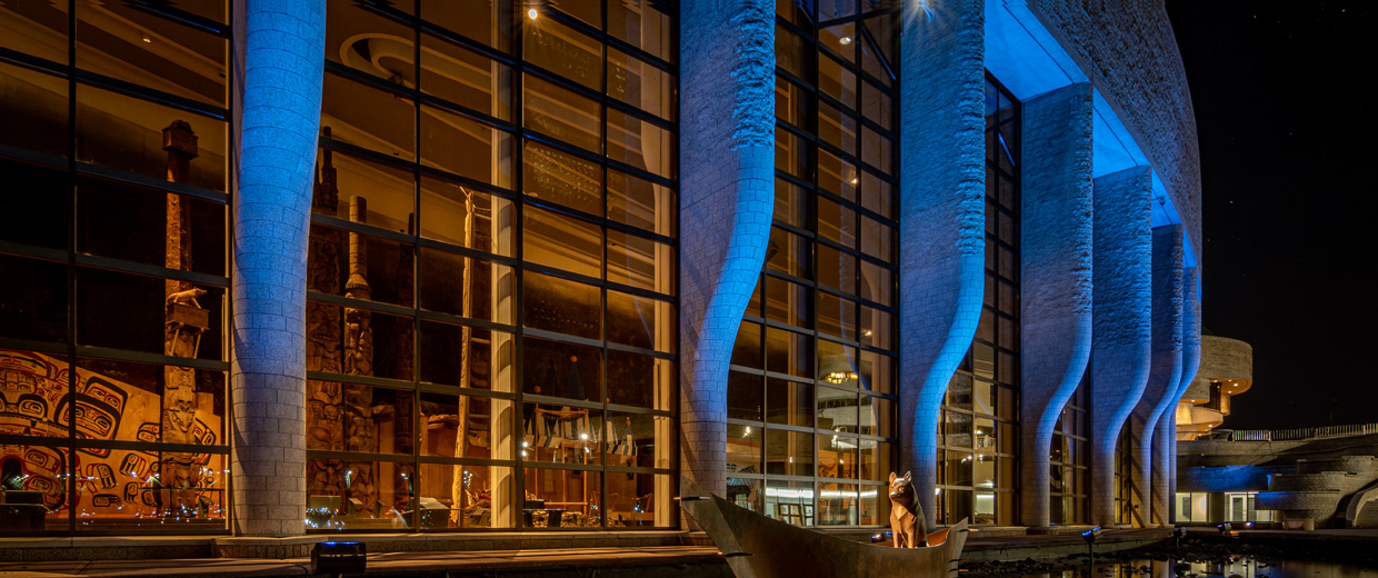 The Canadian Museum of History, located in Ottawa, is a large building with a blue light shining on it.