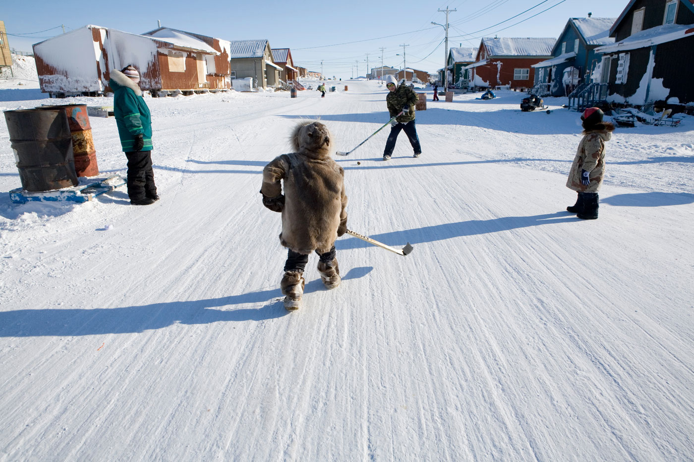 A boy is playing hockey on a snowy street in Ottawa.