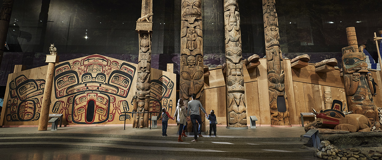 Visitors at the Canadian Museum of History in Ottawa standing in front of totem poles.