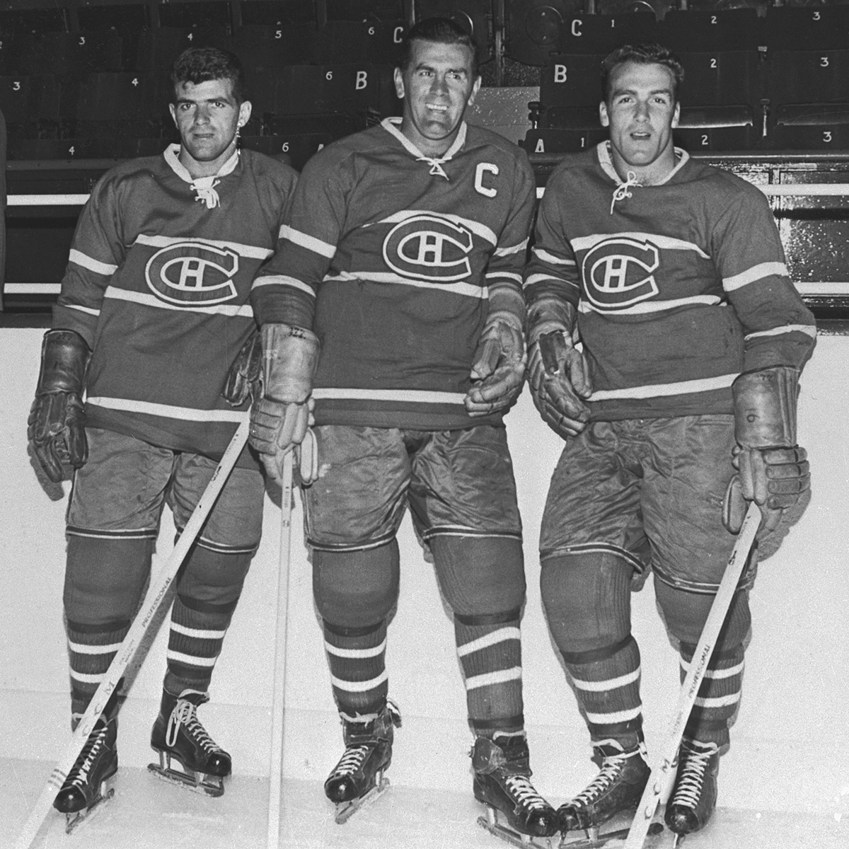 Three men in hockey uniforms posing for a photo at the Canadian Museum of History in Ottawa.