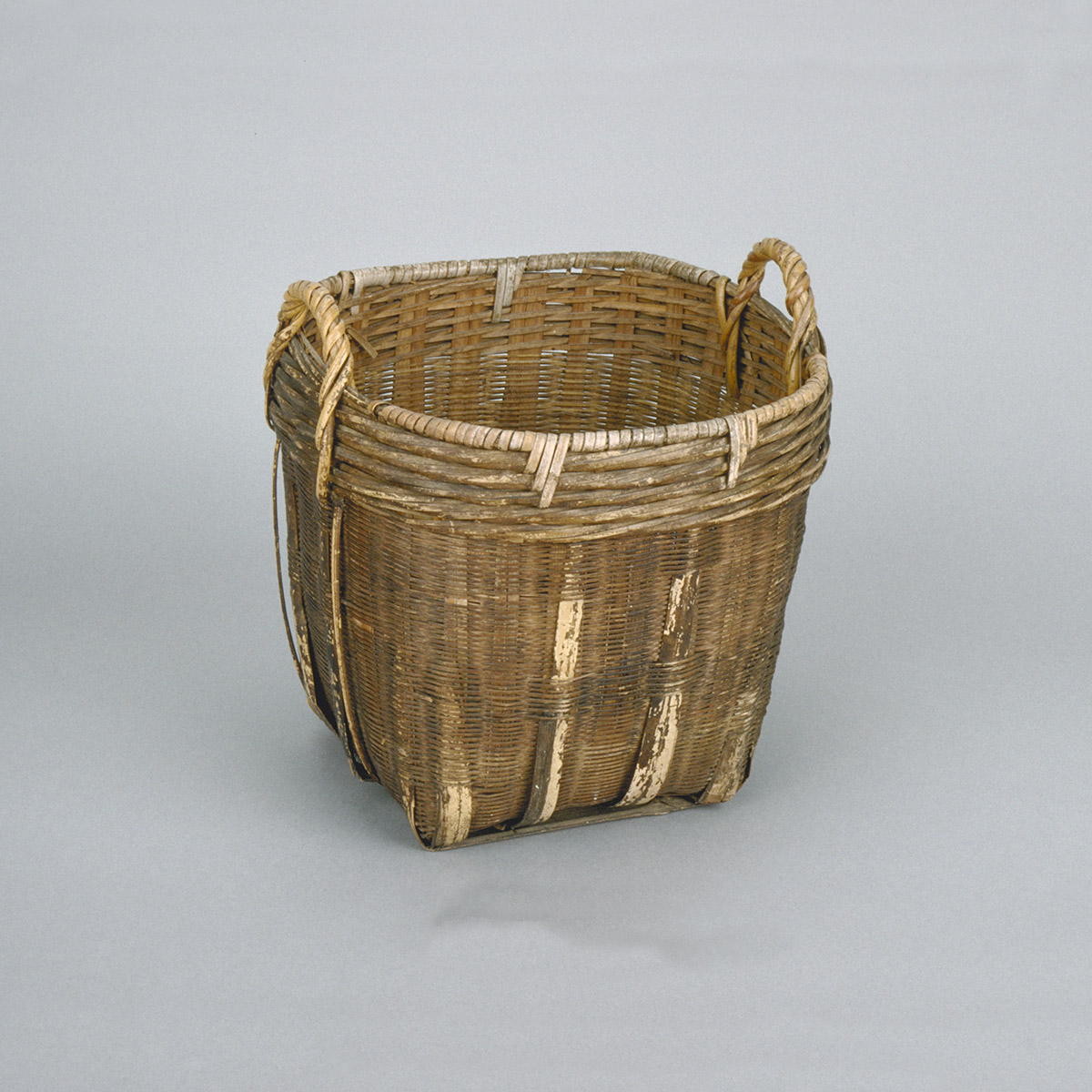 A basket with handles on a white background, showcased at the Canadian Museum of History in Ottawa.