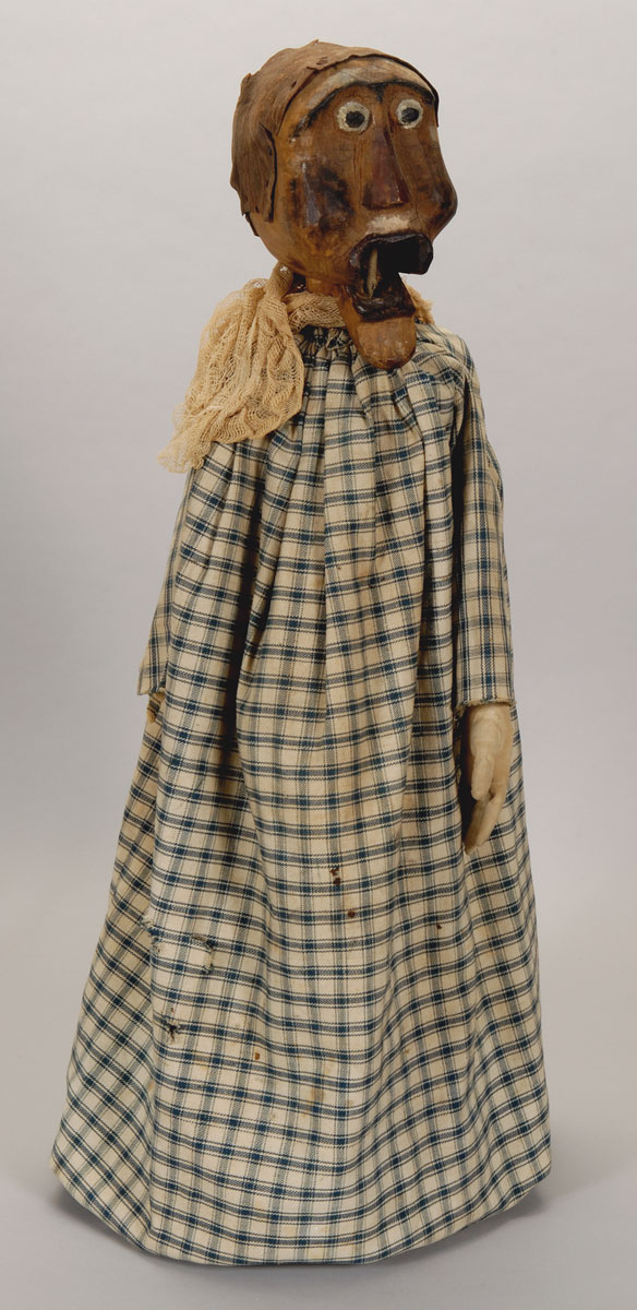 A doll dressed in a blue and white checkered dress on display at the Canadian Museum of History.