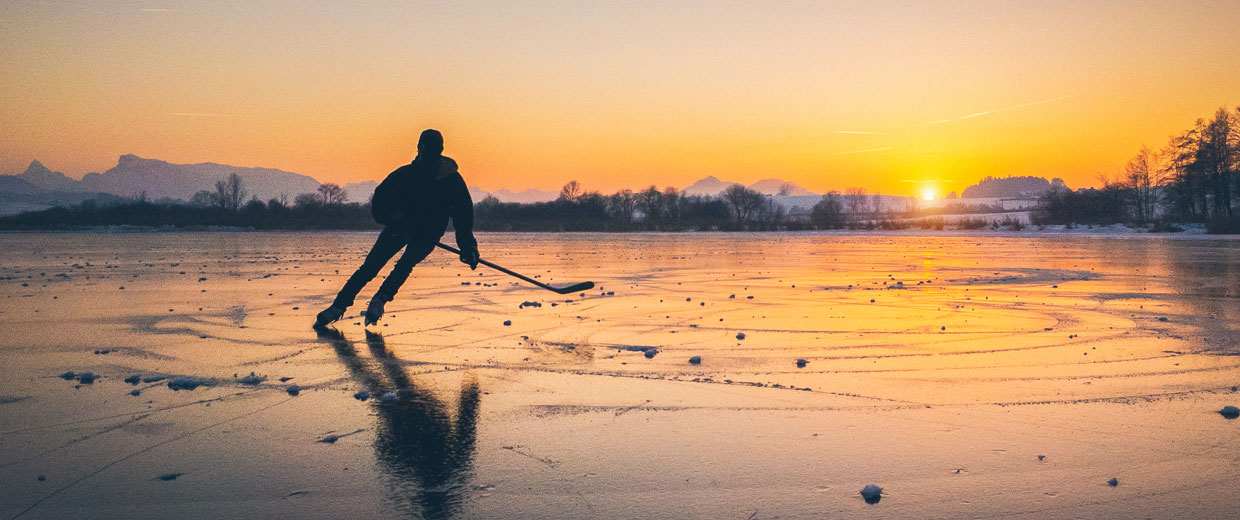 A hockey player skates on a frozen lake.