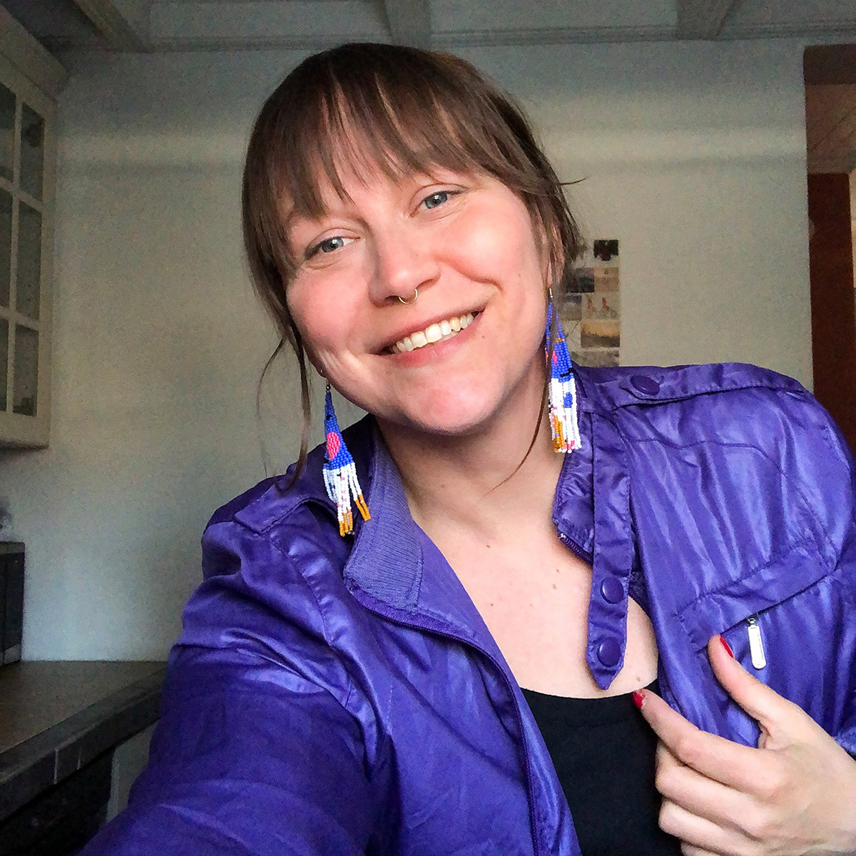 Jaime Black wearing a purple jacket and earrings.