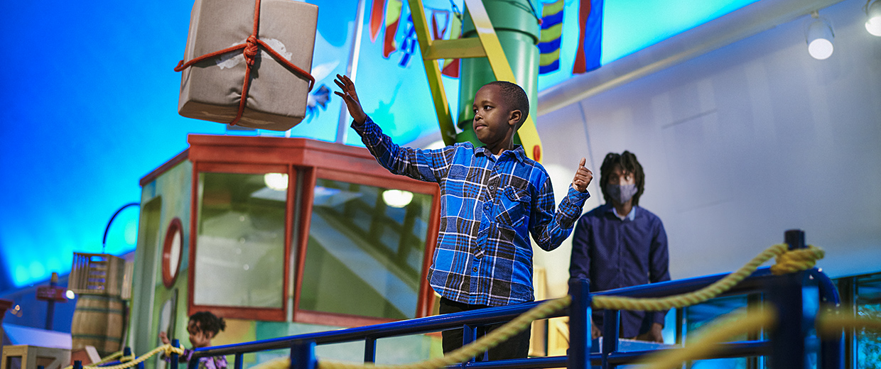 A boy is holding up a box in the Canadian Museum of History in Ottawa.