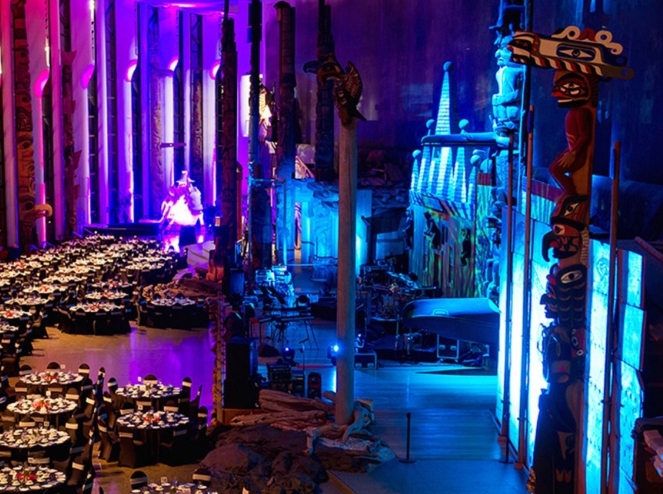 A large hall with tables and chairs set up for a featured event banquet.