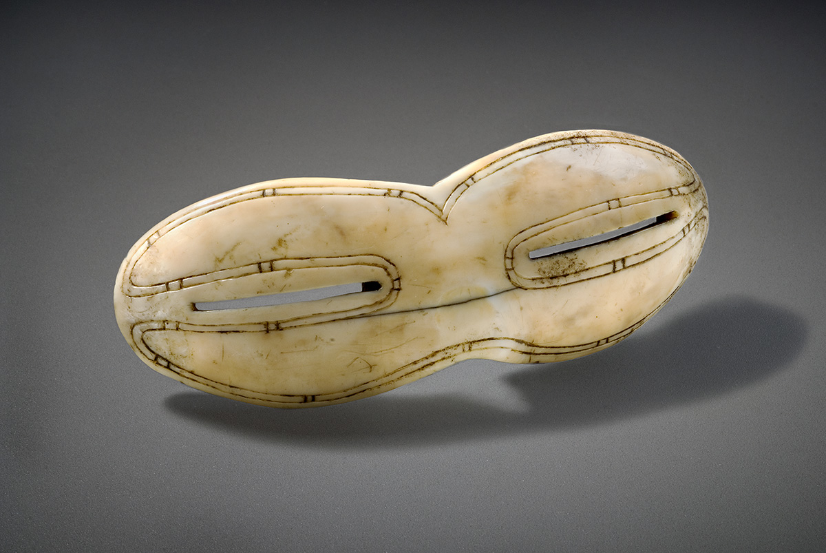 A mask made of ivory and wood on a gray surface showcased at the Canadian Museum of History in Ottawa.