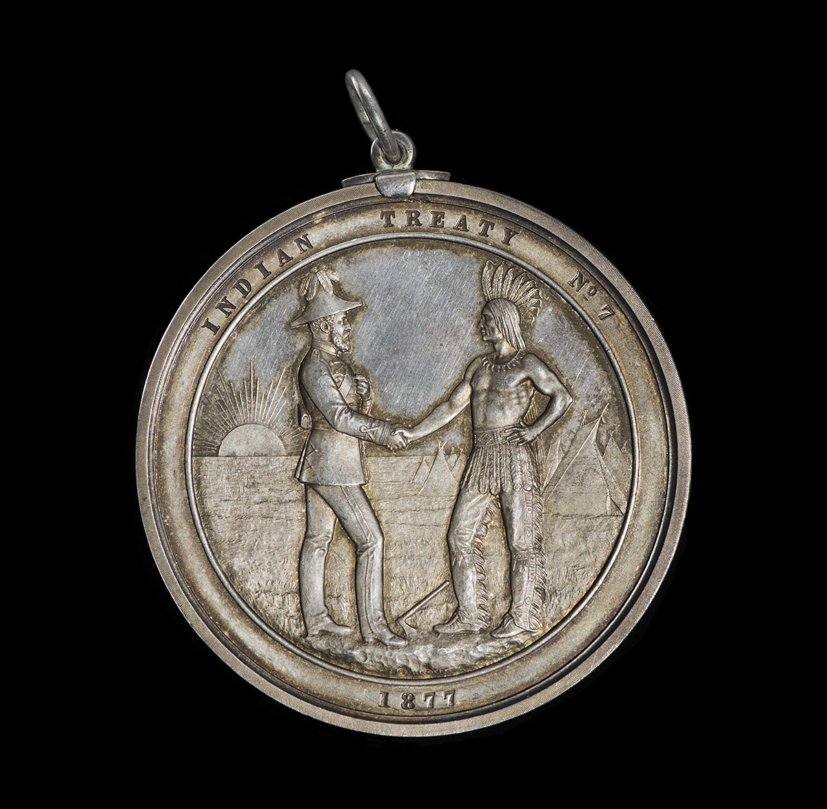 A silver medal with two men shaking hands displayed in the Canadian Museum of History.