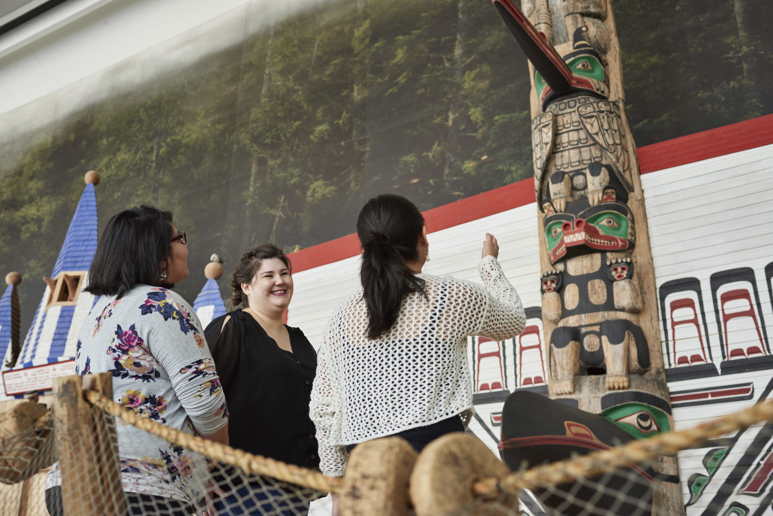 Three women looking at a totem pole in the Canadian Museum of History.