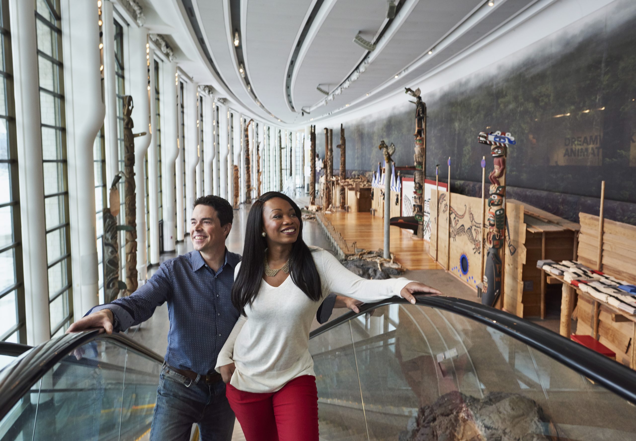 Two people standing on an escalator in the Canadian Museum of History.