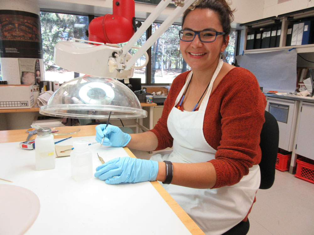 A woman wearing an apron and reviewing an artifact in Ottawa's Canadian Museum of History.