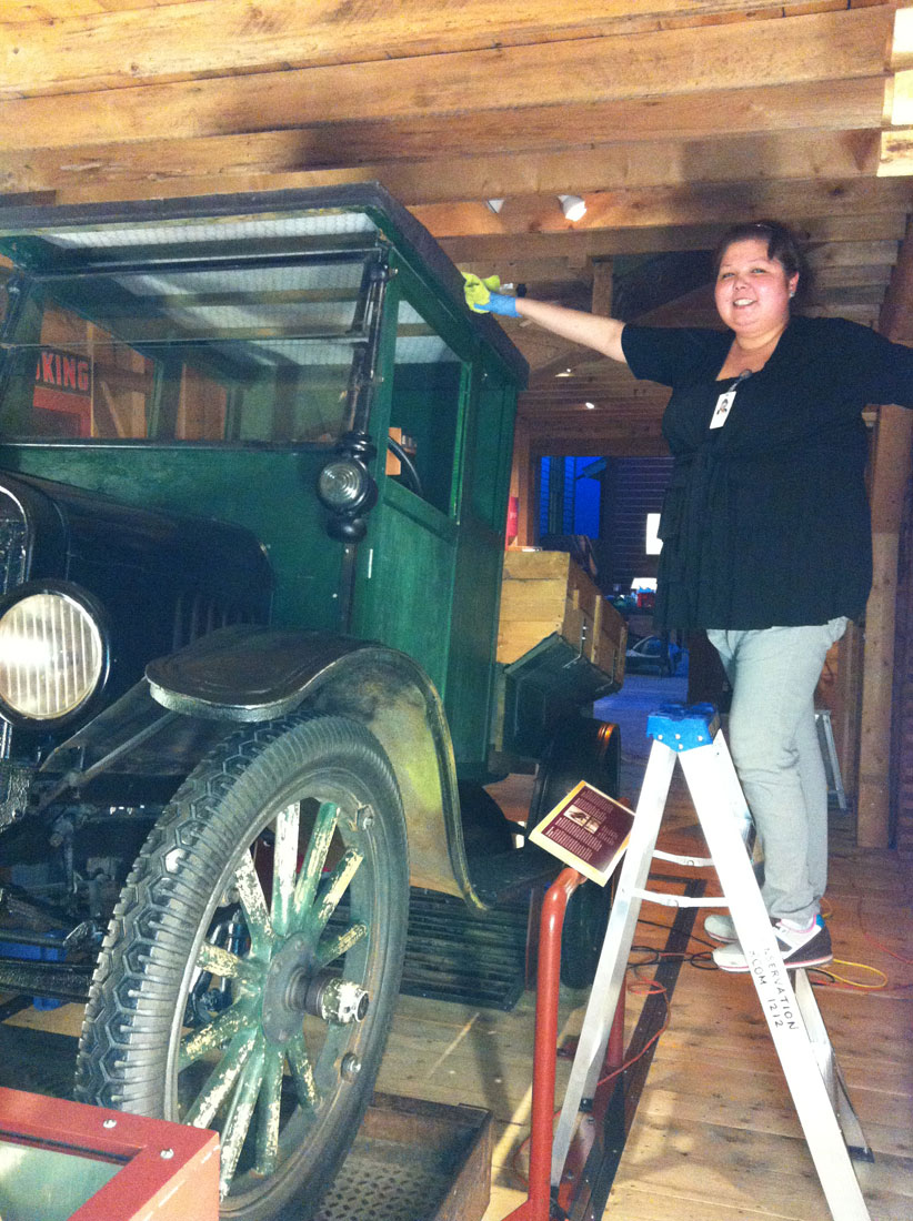 A woman standing on a ladder next to an old truck at the Canadian Museum of History in Ottawa.