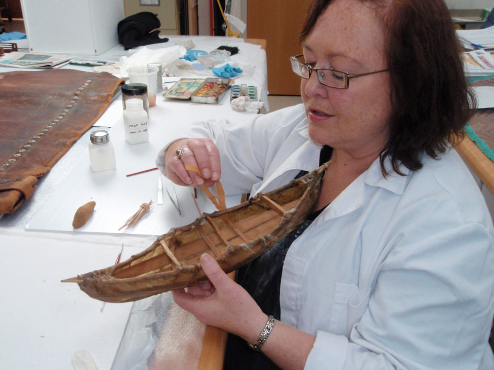 In Ottawa, a woman is working on a wooden boat at the Canadian Museum of History.