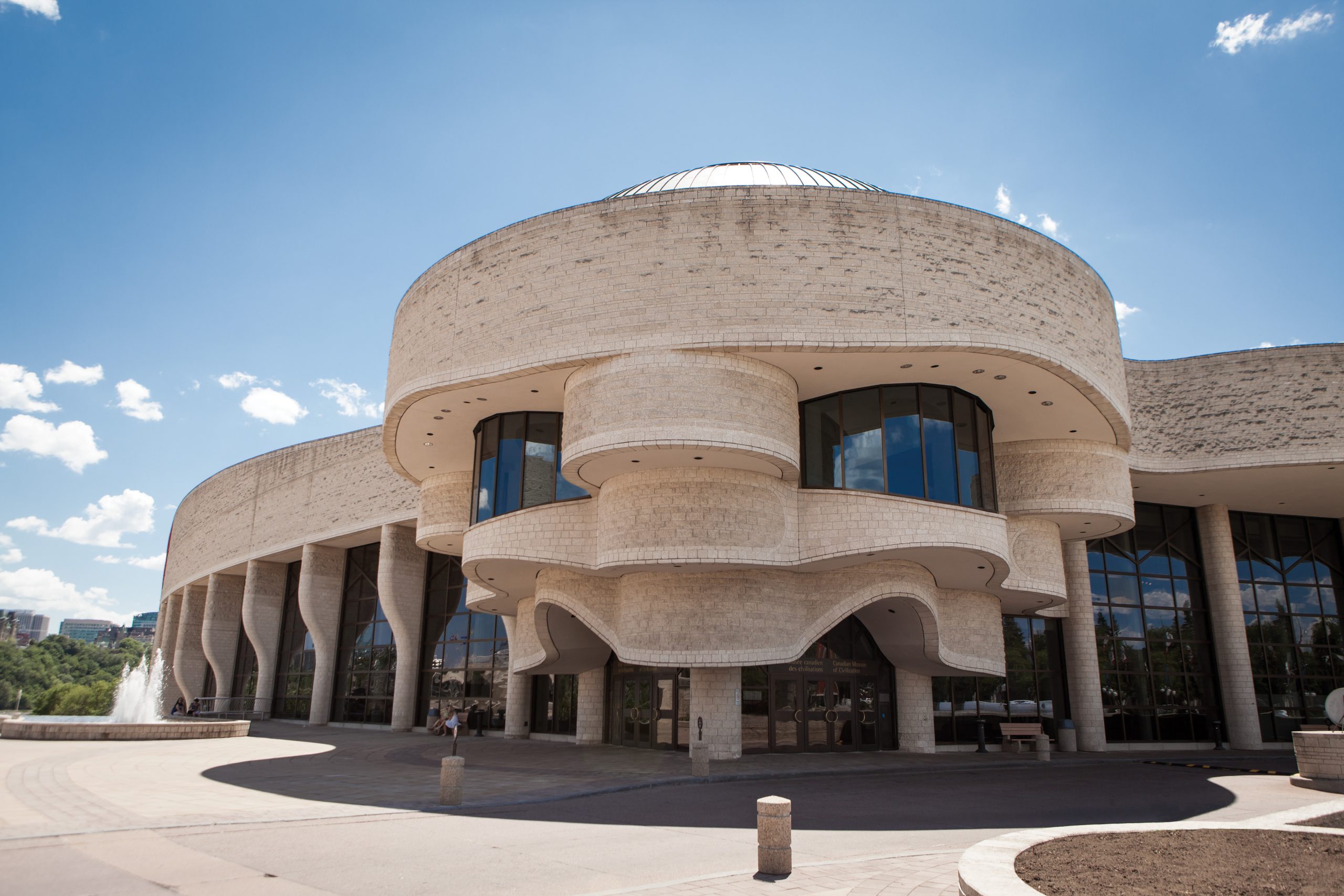 The Canadian Museum of History in Ottawa stands tall, showcasing its impressive stone architecture. A beautiful fountain graces the front of this magnificent building, adding to its grandeur.