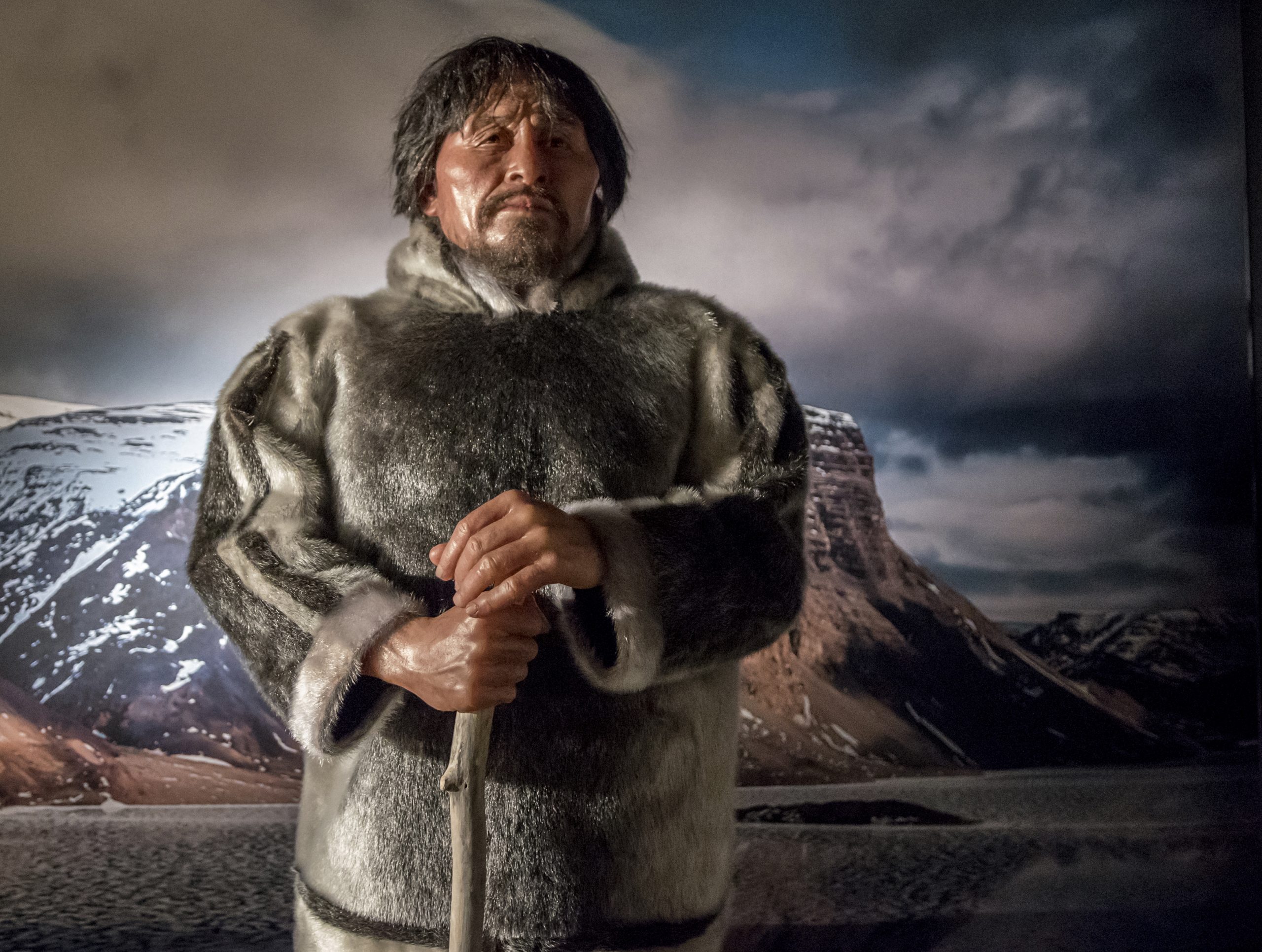 A man in a fur coat standing in front of a mountain at the Canadian Museum of History in Ottawa.