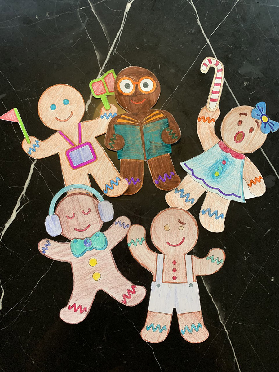 A group of paper, coloured in gingerbread men on a marble table at the Canadian Museum of History.