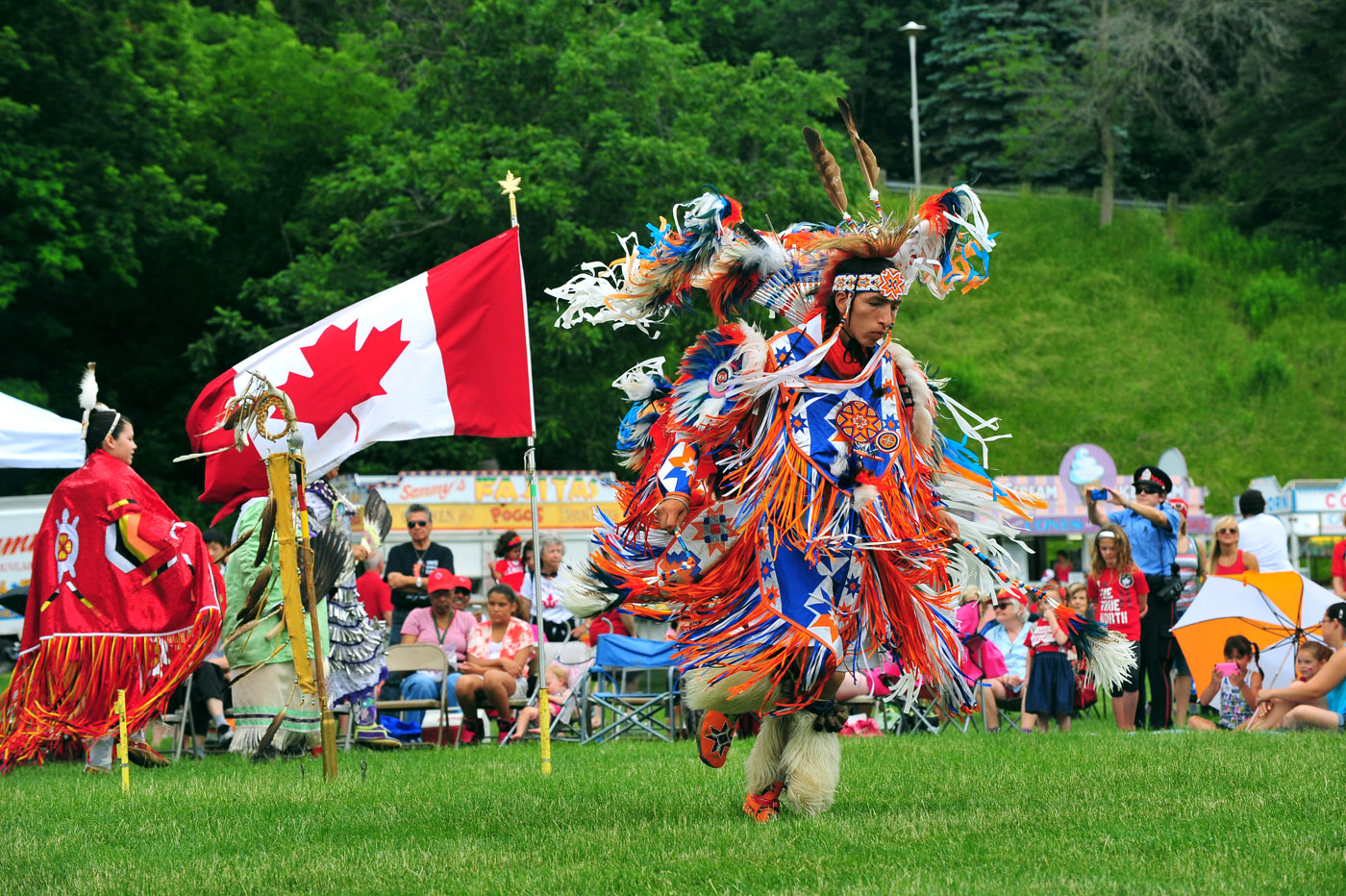 A group of Canadian Indian dancers performing captivating dances during a pow wow in the grassy field.