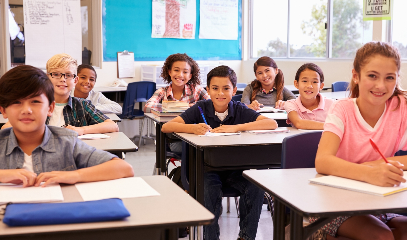 A group of children sitting at desks in a classroom at the Canadian Museum of History.