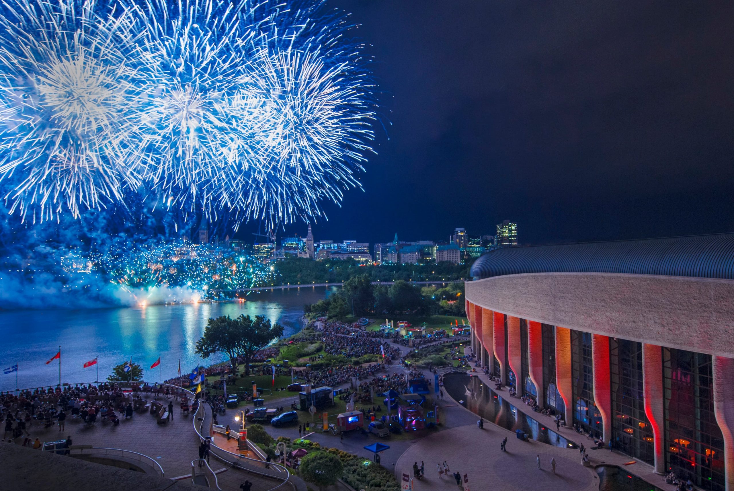 A blue and white fireworks display over a lake during the Canadian Museum of History's annual celebration.