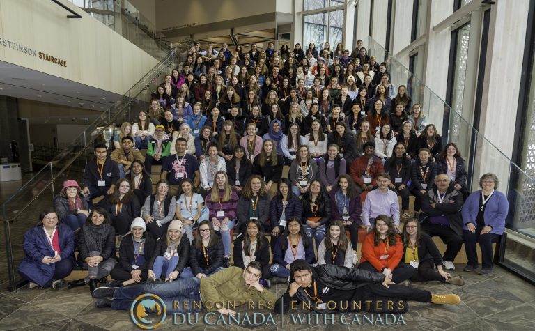 Large, diverse crowd of teenagers and young adults pose for a group photo on a large staircase.